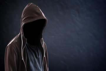 Silhouette of man with a hood and face in the dark, black background with copy space, criminal or hacker concept - obrazy, fototapety, plakaty