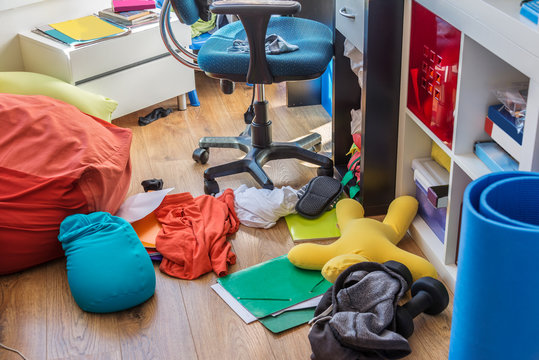 Teenager boy messy bedroom with clothes and colorful pillows on the floor