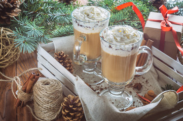 Christmas background with two latte, cookies star, fir branches, cones, gift and spices. Couple coffee with milk and homemade tasty cookies in tray on wooden background. 