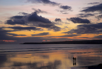 Naklejka na ściany i meble A Couple Walking on Lahinch Beach in the sunset