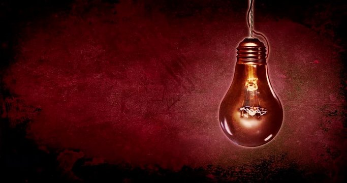 Dark red scary horror background with old bulb on pendulum. Concept background of the mood of anxiety and fear.