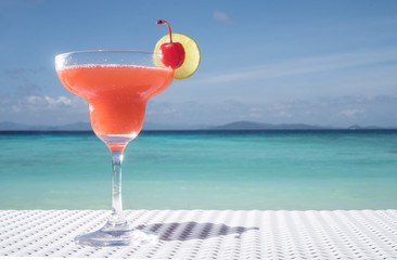 Strawberry Daiquiri cocktail on the white rattan table at the beach restaurant with beautiful blue sea and sky background