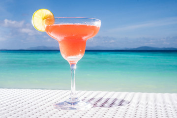 Strawberry Daiquiri cocktail on the white rattan table at the beach restaurant with beautiful blue sea and sky background