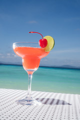 Strawberry Daiquiri cocktail on the white rattan table at the beach restaurant with beautiful blue sea and sky background