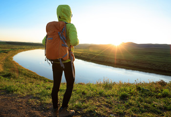  woman hiker enjoy the sunset view on riverside hill top