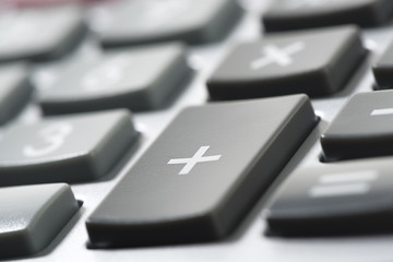 Close up of a calculator with plus sign at the foreground.