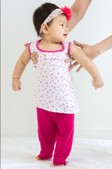 Adorable baby learning to walk with mother's help