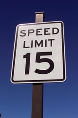The speed limit sign on a close up view and the blue sky in the background.