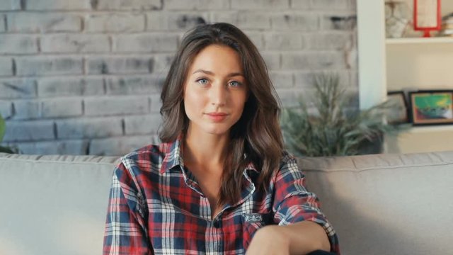 Portrait atractive young woman relaxing on sofa home smiling girl looking camera leisure time happiness satisfaction cute face sitting room close up casual Slow Motion Shot Shot on RED EPIC camera