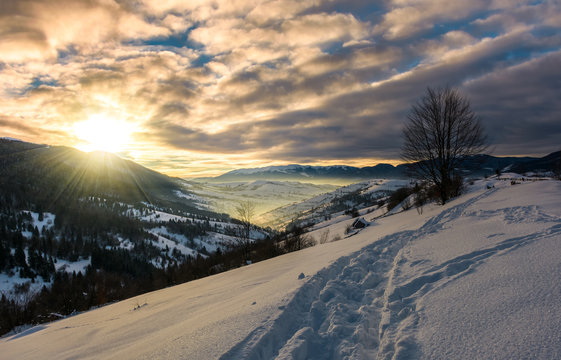 footpath through snowy rural hillside. gorgeous sunrise in mountainous winter countryside