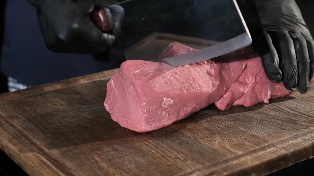 chef chefs cut a piece of meat in black gloves