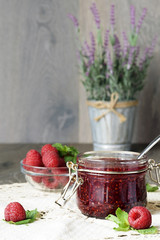 Raspberry jam in a glass jar with fresh raspberry berries