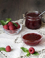 Raspberry jam in a glass jar with fresh raspberry berries