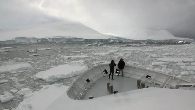 People on research expedition ship float in ice icebergs of Antarctica Ocean. Unique landscape of nature. Quiet and calm wilderness ecotourism. Wildlife on background of white snow desert coast.