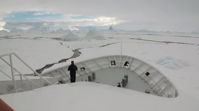 People on research expedition vessel in ice icebergs of Antarctica Ocean. Unique landscape of nature. Quiet and calm wilderness ecotourism. Wildlife on background of white snow desert coast.