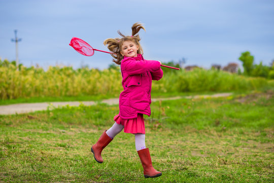 A little girl is running with butterfly net having fun on a fall day