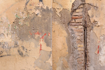 Dirty wall with exposed bricks beneath cement.