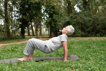 elderly woman practicing yoga outdoors