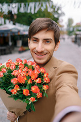 Fototapeta premium Uśmiechnięty mężczyzna Dokonywanie selfie z kwiatami