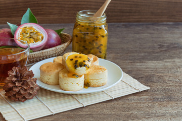 Homemade delicious plain scones serve with passion fruit jam and tea on wood table copy space for background or wallpaper. Scones is traditional English pastry for afternoon tea or coffee break.