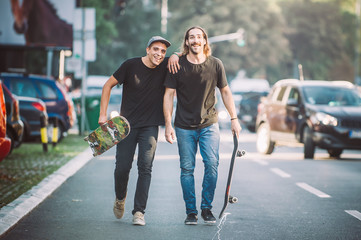 Two pro skateboard rider walking down the street holding skateboards © guruXOX