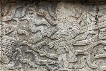 Mayan stone carving in relief showing a king standing surrounded by snakes in Kabah, Mexico.
