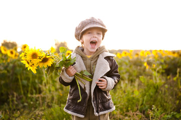 Cheerful little boy in a field of sunflowers.
