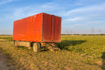 Roter, geschlossener Landwirtschaftsanhänger am rechten Feldrand