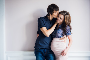 Smiling happy couple waiting for a child leans to each other at home