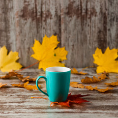 Blue Cup of hot tea. Wooden old vintage background. Autumn leaves. Yellow Red.