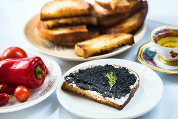 Sliced fried bread with caviar, vegetable and tea.