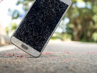Close-up image of old broken and cracked screen smartphone drop down on the floor with copy space