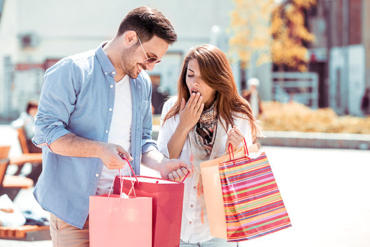 Smiling attractive couple with shopping bags in the city.
