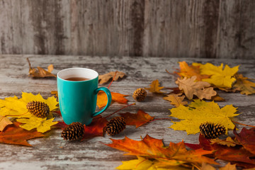 Blue Cup of tea. On a wooden table with Yellow Red Leaves. Autumn.