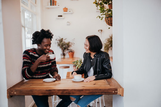 Mixed Race young adult couple drinking coffee in cafe