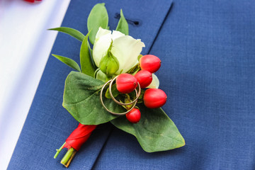wedding rings on boutonniere on lapel of jacket of groom