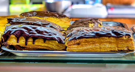 Delicious puffy pastries covered in dark chocolate; dedicated focus.