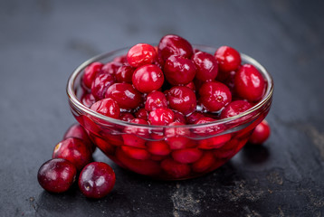 Some fresh made  Cranberries (preserved) on a vintage slate slab (selective focus)