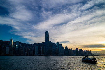 Hong Kong skyline cityscape and ferry traffic on Victoria harbor at twilight sunset