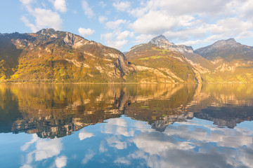 Fototapeta na wymiar Mirror reflection in autumn. Autumn. Mountains and clouds are reflected in the water of Lake Lucerne. Canton of Uri, Switzerland.