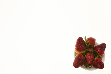Vase with ripe strawberries close-up on a white background.