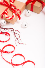 Christmas gift boxes wrapped in craft paper with satin red ribbon bow for christmas present celebration box on white isolated background copy space greeting card frame candy canes white ornament balls