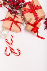 Christmas gift boxes wrapped in craft paper with satin red ribbon bow for christmas present celebration box on white isolated background copy space greeting card frame candy canes white ornament balls