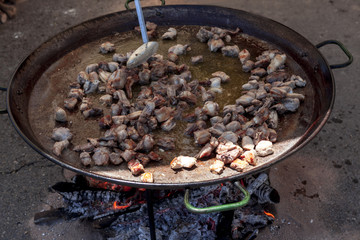 Fried chicken legs. Preparation of chicken paella.national Spanish dish of paella in a large skillet is cooked on an open fire, at the stake