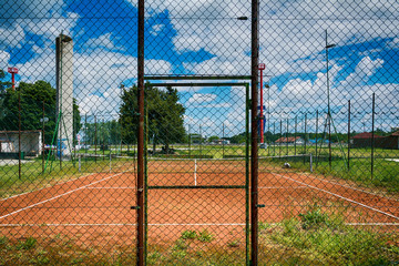 Tennis net at empty red gravel court 