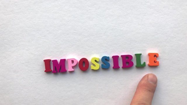 possible. coloured wooden letters on a white sheet of paper.