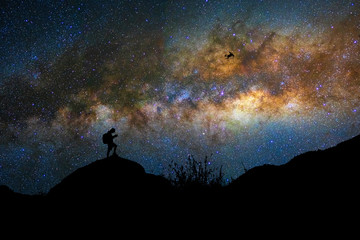 Naklejka na ściany i meble Silhouette of photographer with drone over the milky way on the dark sky background, photographer and transportation with astrophotography concept