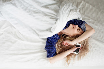 Morning, the woman under the blanket, with a smartphone in hand