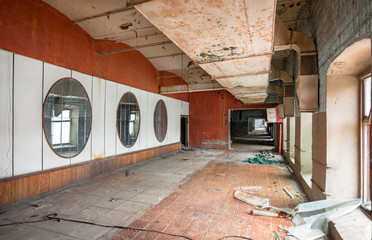 Corridor with a big pipe in the ceiling ventilation. A wall of mirrors on an old abandoned textile...