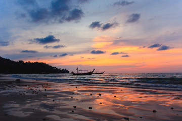 Silhouette of two traditional longtail boats at low tide at sunset on the Kamala beach in Thailand. Tropic travel destination. Meditative and simple seascape with copy space.